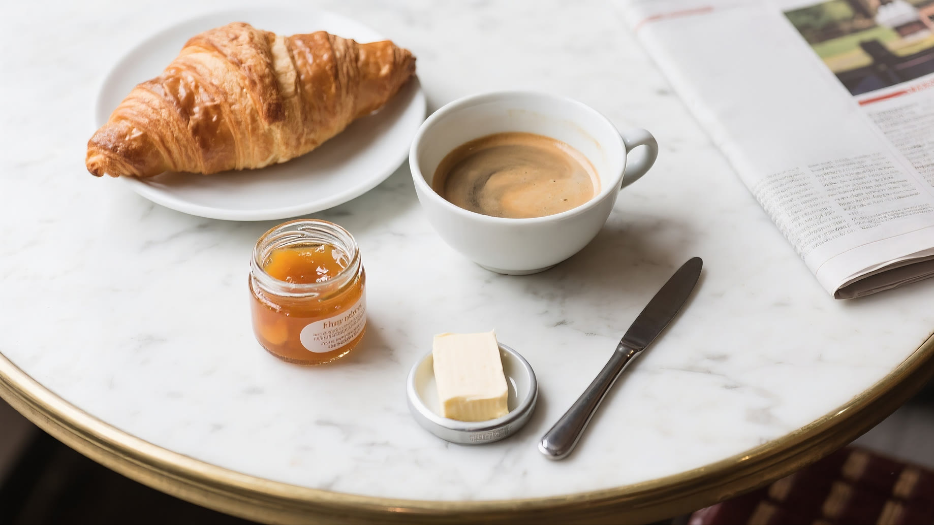 Croissant and café au lait on a marble bistro table