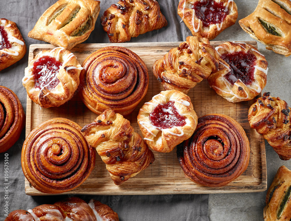 Cinnamon buns and fruit danishes on a wooden board